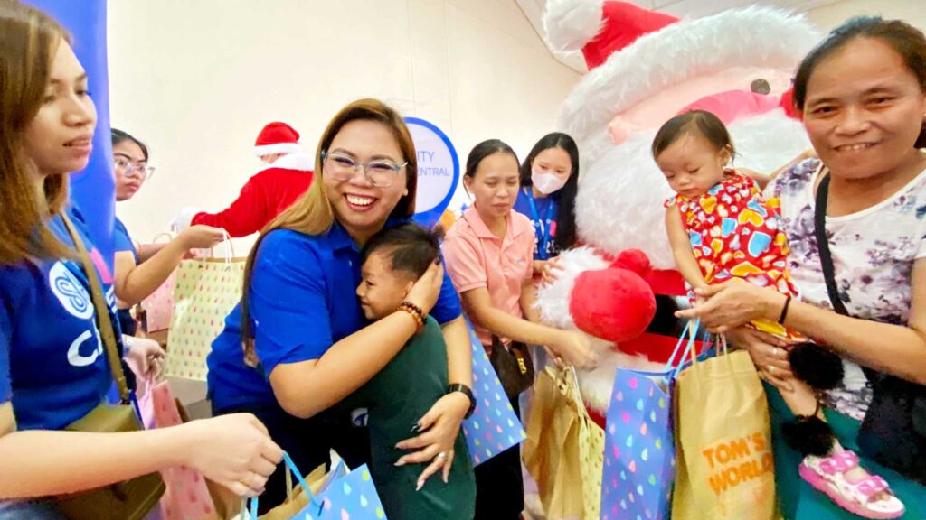 A child embraces SM City Grand Central mall manager Alpha Hernandez, beaming
with joy as they receive gifts during SM City Grand Central and SM Center San- gandaan’s ChriSMiles event.
