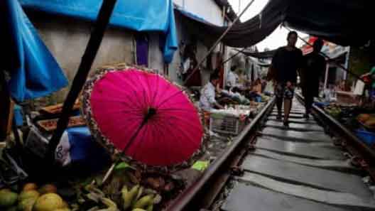 A woman walks at the Maeklong market next to the train tracks, on the outskirts of Bangkok, Thailand.